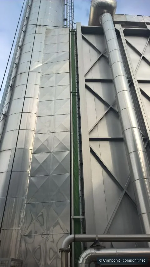 Junta de expansión textil vertical instalada entre una chimenea y un equipo industrial